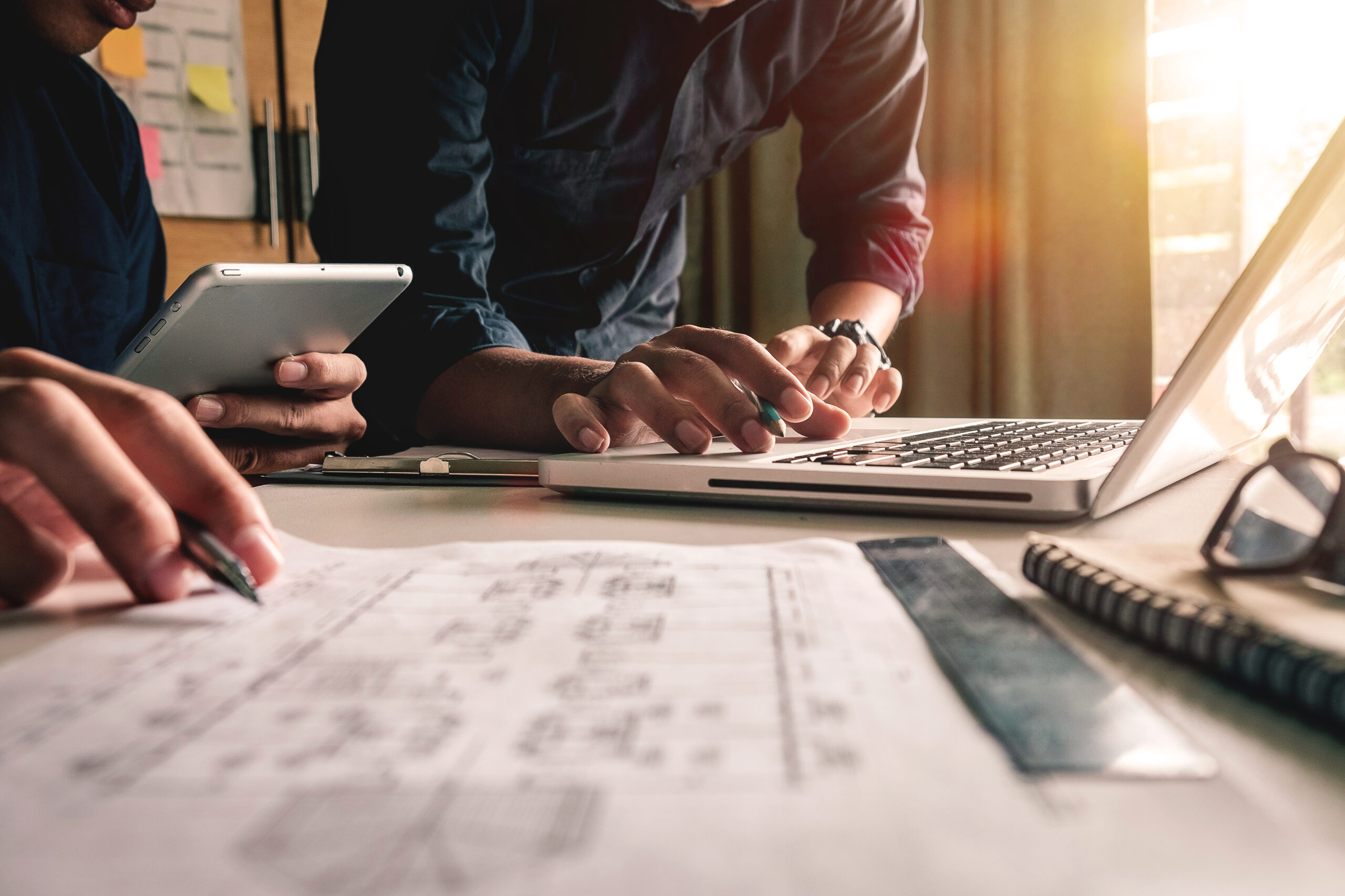 Person working at a desk with a laptop and documents.